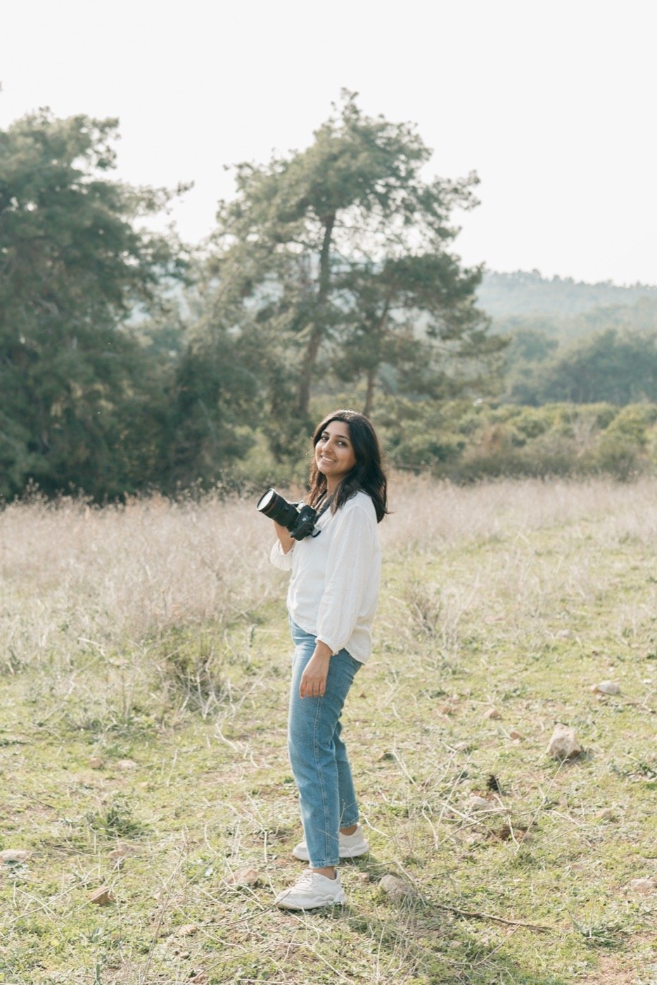 Ahlam Raffii standing in a field with her camera