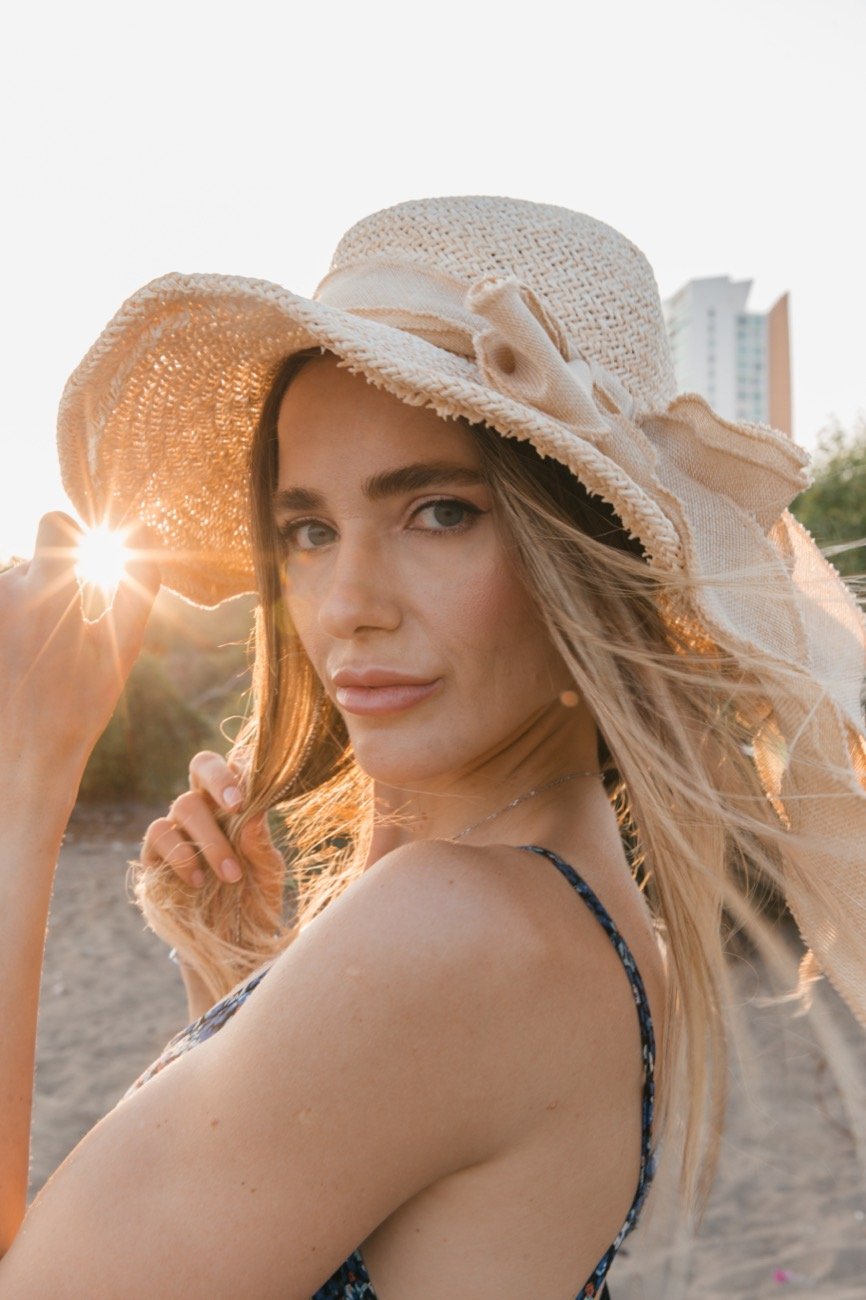 A portrait in a straw hat, the sun behind her