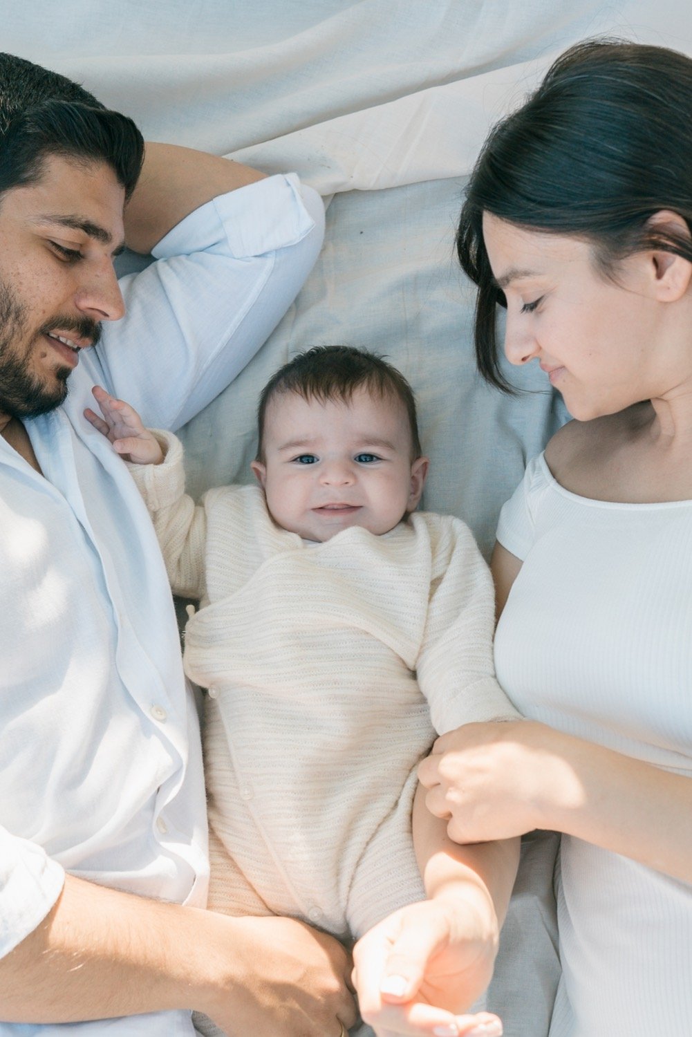 A family lying together with their baby between them